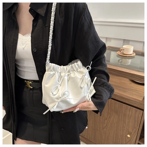 Détail du sac bandoulière blanc plissé avec nœuds en cuir et bandoulière en chaîne