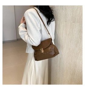 Detailed view of a vintage brown pleated shoulder bag with gold clasp on a female model