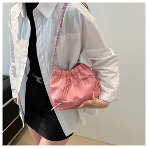 Détail d'un sac seau rose plissé avec trois nœuds et bandoulière chaîne argent