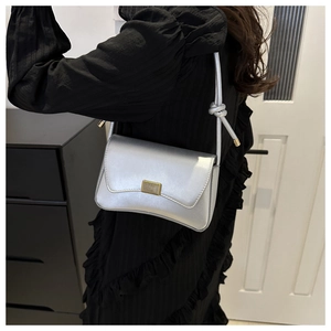 Detail of silver shoulder bag showing the golden clasp and decorative knotted strap