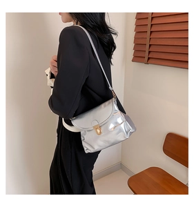 Detail of silver metallic shoulder bag with gold buckle and glossy mirror finish