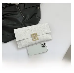 White envelope clutch in crocodile pattern skin shown next to a phone for size reference