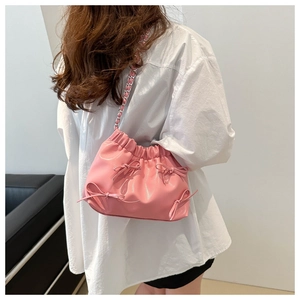 Détail du sac nuage plissé rose avec des nœuds délicats et une bandoulière en chaîne