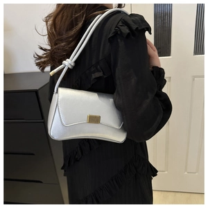 Detail of silver underarm bag featuring a metallic finish and gold vertical buckle