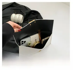 Internal storage view of white woven envelope bag with phone, makeup and accessories
