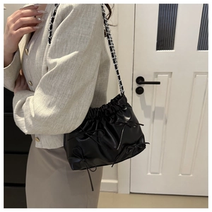 Détail du sac seau plissé noir avec nœuds décoratifs et bandoulière chaîne argent