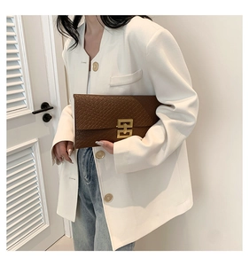 Detail of woven brown envelope clutch bag featuring a rectangular gold metal lock closure