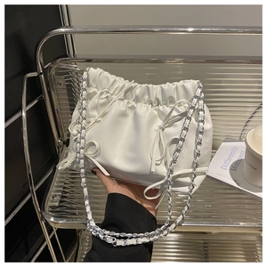 Gros plan d'un sac seau plissé blanc avec nœud décoratif et bandoulière chaîne argentée