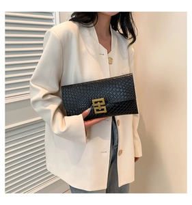 Close-up of black crocodile pattern clutch bag with gold geometric metal buckle detail