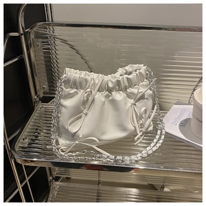 Détail du sac nuage plissé blanc avec nœuds délicats et bandoulière en chaîne argentée