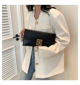 Detailed close-up of a black embossed envelope clutch with a luxury gold hardware buckle