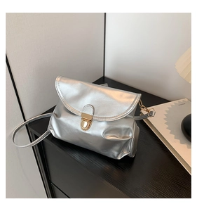 Detail shot of silver metallic crossbody bag featuring a curved flap and gold-tone lock clasp