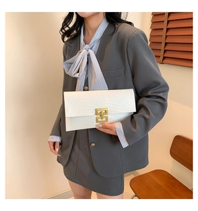 Macro detail of white crocodile-embossed envelope clutch with vintage gold buckle