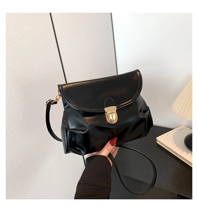 Detail of black vintage PU leather crossbody bag featuring gold buckle and pleated texture