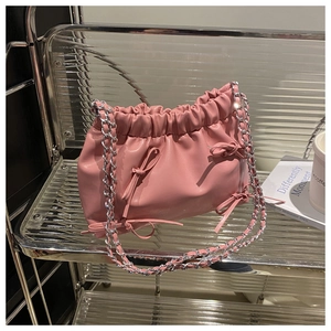 Détail du sac bandoulière plissé rose avec nœuds en cuir et chaîne argentée