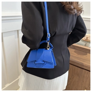 Dettaglio della mini borsa in pelle blu reale con base curva ed elegante manico superiore