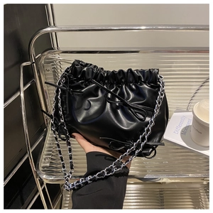Détail du sac seau plissé noir avec nœuds en cuir et bandoulière chaîne argentée