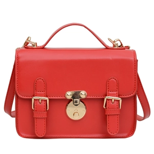 Red faux leather crossbody bag with gold round buckle and top handle on white background
