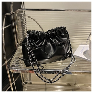 Détail du sac seau noir plissé avec nœuds décoratifs et bandoulière chaîne