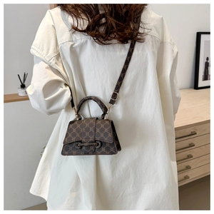Dettaglio della borsa a mano vintage marrone con monogramma indossata su una camicia bianca