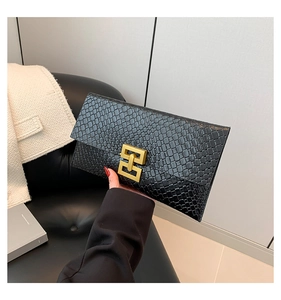 Detail of black crocodile texture envelope clutch with elegant gold metal buckle