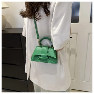 Dettaglio della mini borsa verde brillante in pelle martellata indossata da modella