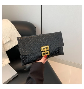 Close-up of black envelope clutch bag featuring woven texture and gold interlocking buckle