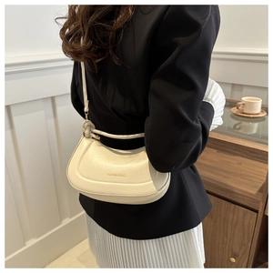 Detail of minimalist cream-white underarm bag with gold lettering and knotted metal hardware