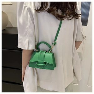 Dettaglio di una micro borsa quadrata verde minimalista con trama litchi e fibbia