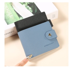 Close-up of pebble leather bi-fold card holder with snap closure and morandi blue finish