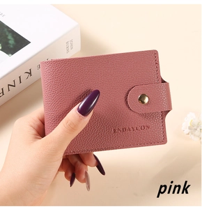 Close-up of pink lychee leather card holder with gold snap button and stitched edges