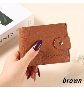 Detailed view of brown litchi grain leather wallet with golden snap button closure