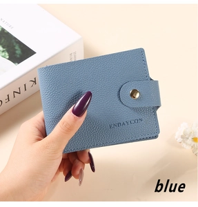 Close-up of blue lychee grain leather card holder with gold snap and embossed logo