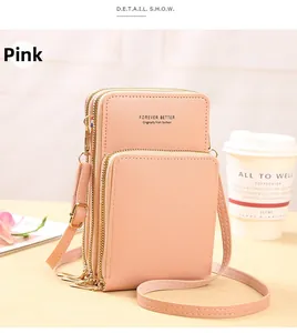 Close-up of pink crossbody phone bag with three zippers and adjustable strap on a cafe table