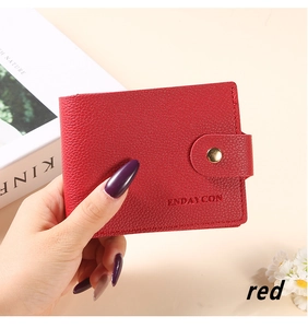 Close-up of red litchi grain leather card holder with a golden button closure