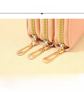 Detail of light pink leather bag featuring triple golden zipper compartments and fine texture