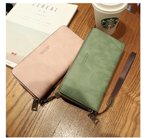 Detail of long zippered wallets in pink and green on a wooden desk with wrist straps