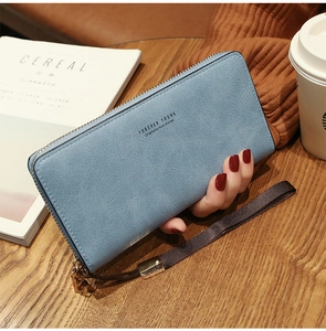 Detail of light blue long zipper wallet with Forever Young text on a wooden table
