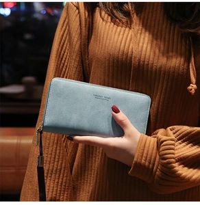 Fashionable light blue long clutch wallet with zipper and wrist strap held by model