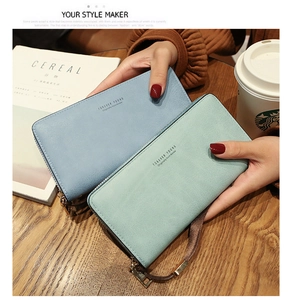 Detail of grey-blue and pale green long wallets with matte texture and gold hardware