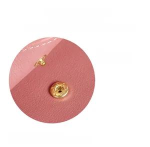 Detail view of pink lychee leather handbag featuring a secure gold magnetic safety lock