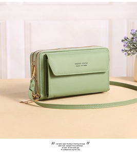 Detail view of green faux leather crossbody bag with dual zippers and front magnetic pocket