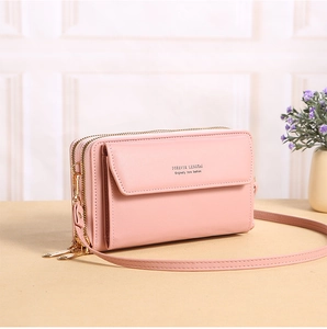 Detail of light pink PU leather crossbody bag with dual zippers and gold lettering