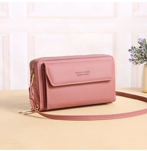 Detail view of pink crossbody bag with dual zippers and front pocket on table