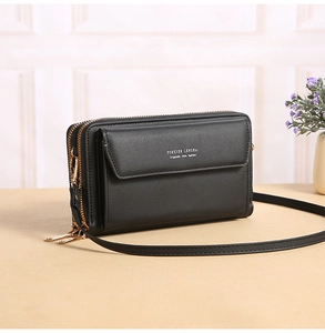 Detail of black crossbody phone bag with double zippers and golden metal hardware