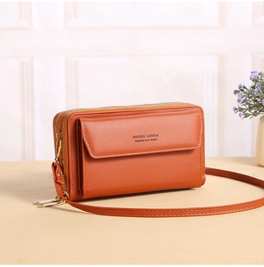 Detail of a bright orange PU leather crossbody bag featuring dual zippers and metal logos