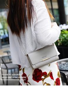 Détail d'un sac bandoulière en cuir gris avec ferrures dorées et structure multicouche