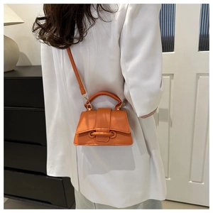 Dettaglio di una mini borsa a tracolla arancione vivace con fibbia decorativa elegante