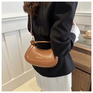 Close-up of stylish brown leather hobo bag worn as an underarm shoulder bag for women