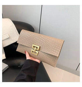 Detailed view of the woven texture and golden interlocking metal clasp on the beige clutch